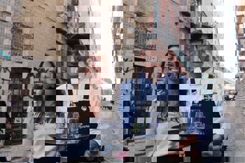 A young woman smiles with a server at É Um Restaurante